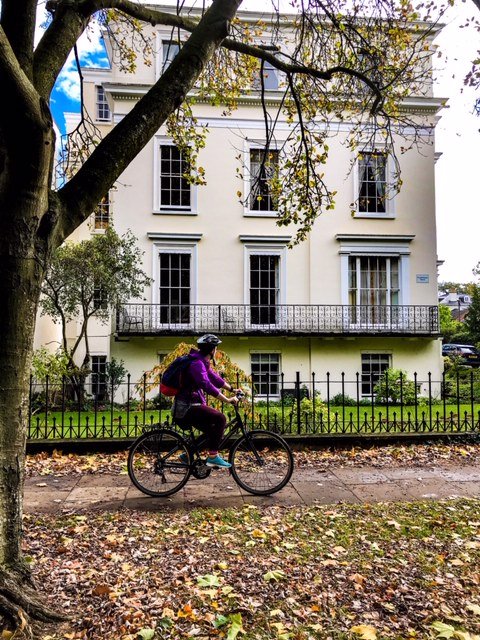 Cyclist pedalling past regency buildings in Cheltenham